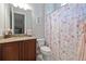 Cozy bathroom features a wooden vanity, shower with floral curtain, and an adorable pink robe at 4512 Cheval Blvd, Lutz, FL 33558
