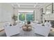 Living area features bright neutral colors, white armchairs, and backyard views to the pool at 4512 Cheval Blvd, Lutz, FL 33558