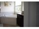 Bright bathroom features a soaking tub, dark vanity, and a sunlit window at 4888 Sevilla Shores Dr, Wimauma, FL 33598