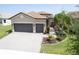 Beautiful home exterior with a tile roof, paver driveway, two car garage, and professional landscaping at 4888 Sevilla Shores Dr, Wimauma, FL 33598