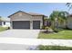 Beautiful home exterior with a tile roof, paver driveway, two car garage, and professional landscaping at 4888 Sevilla Shores Dr, Wimauma, FL 33598