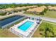 Aerial view of a pool with an adjacent building, surrounded by lush landscaping, and a scenic pond at 4943 New England Blvd # 105, New Port Richey, FL 34652