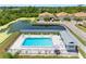 Aerial view of pool and pond surrounded by manicured lawns and low-maintenance landscaping at 4943 New England Blvd # 105, New Port Richey, FL 34652
