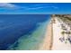 An aerial view featuring sandy beach, clear waters, and beachside cabanas along the coast at 4943 New England Blvd # 105, New Port Richey, FL 34652