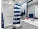 Bright bathroom with a shower-tub combo, blue striped shower curtain, and vanity with sink at 4943 New England Blvd # 105, New Port Richey, FL 34652