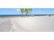 A serene beach with palm trees, turquoise chairs, and a wide expanse of sand leading to the ocean at 4943 New England Blvd # 105, New Port Richey, FL 34652