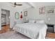 Main bedroom featuring a white bed, wood floors, ceiling fan, and eclectic wall art at 513 W Paris St, Tampa, FL 33604
