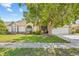 Inviting one-story home with lush front yard, large shade tree, and charming architectural details at 5434 Wellfield Rd, New Port Richey, FL 34655