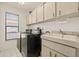 Modern laundry room with ample cabinetry, sleek appliances, and a sink at 5434 Wellfield Rd, New Port Richey, FL 34655