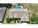 Overhead view showcases a well-maintained home with a new roof, complemented by a screened-in pool and landscaping at 5465 Chestnut Ridge Rd, Dade City, FL 33523