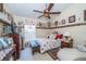 A decorative bedroom with a floral bed set, ornate furniture, a ceiling fan, and a large window with blinds at 5465 Chestnut Ridge Rd, Dade City, FL 33523