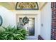 Close-up of the home's entry door, accented with decorative glass, wreath, and sidelight windows at 5465 Chestnut Ridge Rd, Dade City, FL 33523