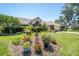 Well maintained front yard with an array of colorful plants, green grass, and mature trees surrounding the home at 5465 Chestnut Ridge Rd, Dade City, FL 33523