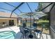 Screened-in patio area featuring an outdoor dining set, a partial view of a pool, and backyard views at 5465 Chestnut Ridge Rd, Dade City, FL 33523