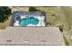 Aerial view of a kidney-shaped pool in a screened enclosure, complete with lounge chairs and an umbrella at 5465 Chestnut Ridge Rd, Dade City, FL 33523