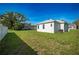 View of the spacious backyard with lush green grass, trees and white privacy fence at 6215 N 44Th St, Tampa, FL 33610