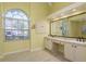 Bathroom featuring double sinks, vanity area, large arched window and tile flooring at 627 Belted Kingfisher N Dr, Palm Harbor, FL 34683