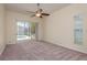 Bright bedroom with carpet, ceiling fan, and sliding glass doors leading to a screened-in pool area at 627 Belted Kingfisher N Dr, Palm Harbor, FL 34683