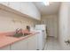 Bright laundry room with white cabinetry, pink countertops, sink, and modern washer and dryer at 627 Belted Kingfisher N Dr, Palm Harbor, FL 34683