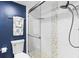 Modern bathroom features a walk-in glass shower, blue accent wall, and sleek fixtures at 8103 Bardmoor Pl # 203G, Seminole, FL 33777