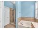Bathroom featuring a glass shower, soaking tub, neutral tiling, and blue walls at 11808 Holly Crest Ln, Riverview, FL 33569