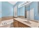 Bathroom with a large vanity, soaking tub, tiled shower, and window with shutters at 11808 Holly Crest Ln, Riverview, FL 33569
