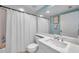 Bathroom with a shower behind a decorative white curtain, white vanity, and large mirror reflecting natural light at 1200 Country Club Dr # 6302, Largo, FL 33771
