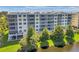 Exterior view of condo building overlooking a pond, featuring balconies, lush trees, and well-maintained landscaping at 1200 Country Club Dr # 6302, Largo, FL 33771