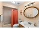 Cozy bathroom featuring a tiled shower-tub combo and a charming, round wicker-framed mirror at 13598 Park Blvd, Seminole, FL 33776