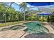 Inviting kidney-shaped pool and spa with brick surround in screened lanai featuring lush tropical landscaping at 13598 Park Blvd, Seminole, FL 33776