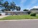 Charming single-story home featuring a well-manicured lawn, a cozy outdoor dining area, and an attached garage at 13725 Bermuda Dr, Seminole, FL 33776