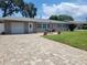 Single-story home with a paver driveway, attached garage, and manicured front lawn at 13725 Bermuda Dr, Seminole, FL 33776