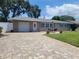 Charming single-story home with a paver driveway, attached garage, and a manicured lawn at 13725 Bermuda Dr, Seminole, FL 33776