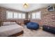 This trendy bedroom features a brick accent wall, shuttered windows, and light wood floors at 1382 52Nd Ne Ave, St Petersburg, FL 33703