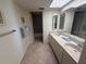 Bathroom with double sink vanity, large mirror, tile floor and open doorway to bathtub and toilet area at 14950 Gulf Blvd # 603, Madeira Beach, FL 33708