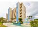 Stunning view of the Ocean Sands building with meticulous landscaping and beautiful water features in the foreground at 14950 Gulf Blvd # 603, Madeira Beach, FL 33708