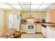 A kitchen features white appliances, tile floors and a dining table at 14950 Gulf Blvd # 603, Madeira Beach, FL 33708
