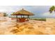 View of Tiki hut wet bar with chairs overlooking patio and sandy beach in the background at 14950 Gulf Blvd # 603, Madeira Beach, FL 33708