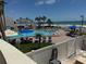 Aerial view of large outdoor pool with sunbathers, lounge chairs and umbrellas overlooking the ocean at 14950 Gulf Blvd # 603, Madeira Beach, FL 33708