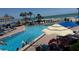 Resort-style swimming pool with beach access and various lounge chairs, umbrellas, and palm trees for a relaxing vacation experience at 14950 Gulf Blvd # 603, Madeira Beach, FL 33708