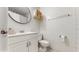 Well-lit bathroom with a white single sink vanity, round mirror, toilet, and towel rack at 1720 Chrysler Ave, Sarasota, FL 34234
