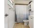 Well-lit bathroom featuring a shower with curtain, toilet, and cabinet at 1720 Chrysler Ave, Sarasota, FL 34234