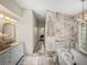 Bright bathroom showcasing marble tiling, a bathtub, a glass shower, and a vanity with a stylish mirror at 18003 Arbor Crest Dr, Tampa, FL 33647