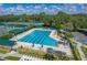 Community lap pool with ample lounge seating, shade umbrellas, and well-maintained tennis courts on a sunny day at 18003 Arbor Crest Dr, Tampa, FL 33647