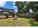 A backyard with green grass, a wooden fence, a palm tree, and screened in pool area at 1801 Sagebrush Rd, Plant City, FL 33566