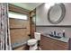 Updated bathroom with brown tiled shower, commode, and vanity with decorative round mirror at 1801 Sagebrush Rd, Plant City, FL 33566