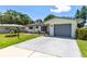 Charming single-story home with a well-manicured lawn and a gray two-car garage at 1809 Elmwood Dr, Oldsmar, FL 34677