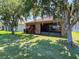 Scenic backyard view featuring a screened patio, lush lawn, mature trees, and a glimpse of the home's exterior at 18107 Canal Pointe St, Tampa, FL 33647