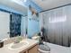 Bathroom featuring blue walls, a shower-tub combo, vanity with sink, and decorative mirror and towel rack at 18107 Canal Pointe St, Tampa, FL 33647