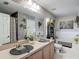 Bathroom with a large mirror, double sinks, decorative accents, and a combined tub-shower at 18107 Canal Pointe St, Tampa, FL 33647